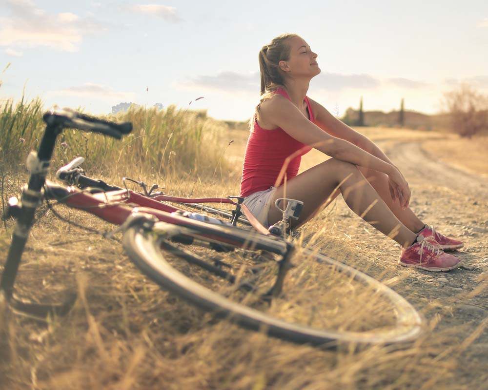 Happy young women sitting next to her bike after having successful individual counseling services