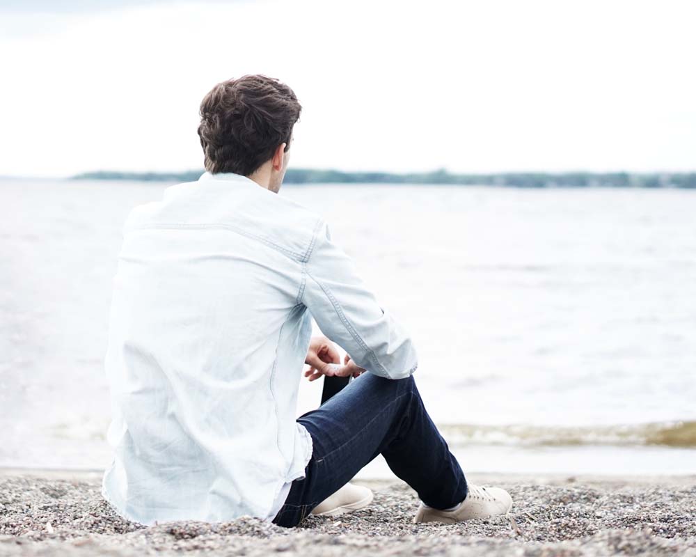 Young man sitting next to Conroe Lake in Texas after successful individual counseling services